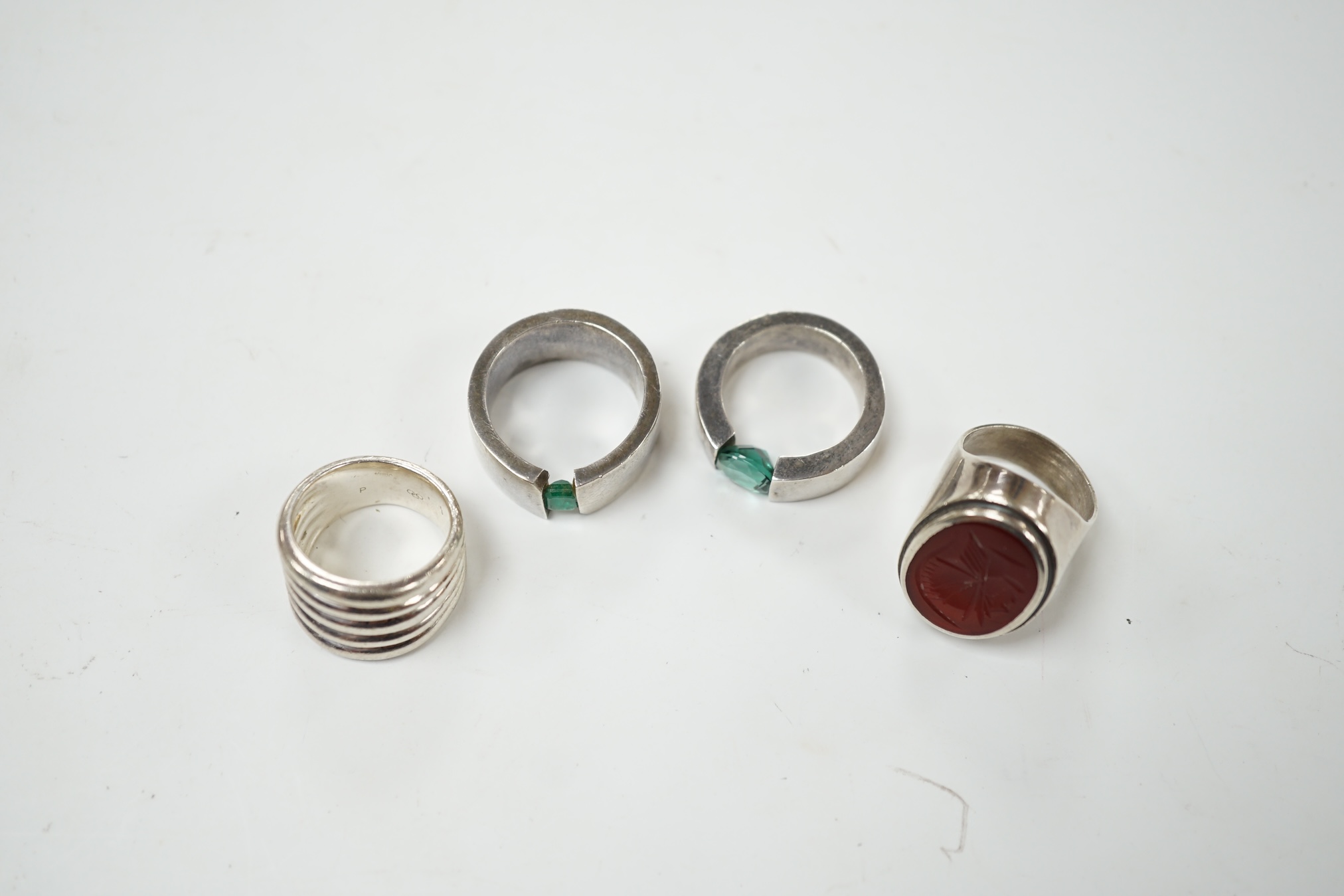 Two modern silver rings, one with coiled shank, the other set with intaglio carnelian and two other white metal rings, one set wit an emerald, the other green quartz, maker's mark P&T. Condition - fair